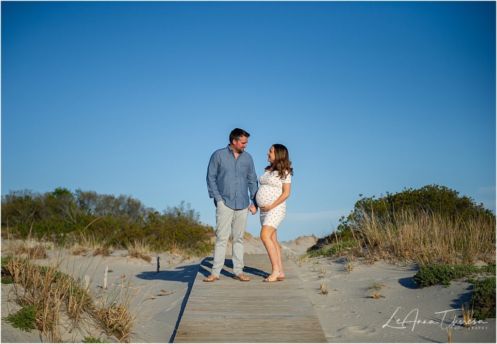 couple hold hands and look at each other maternity photos on LBI