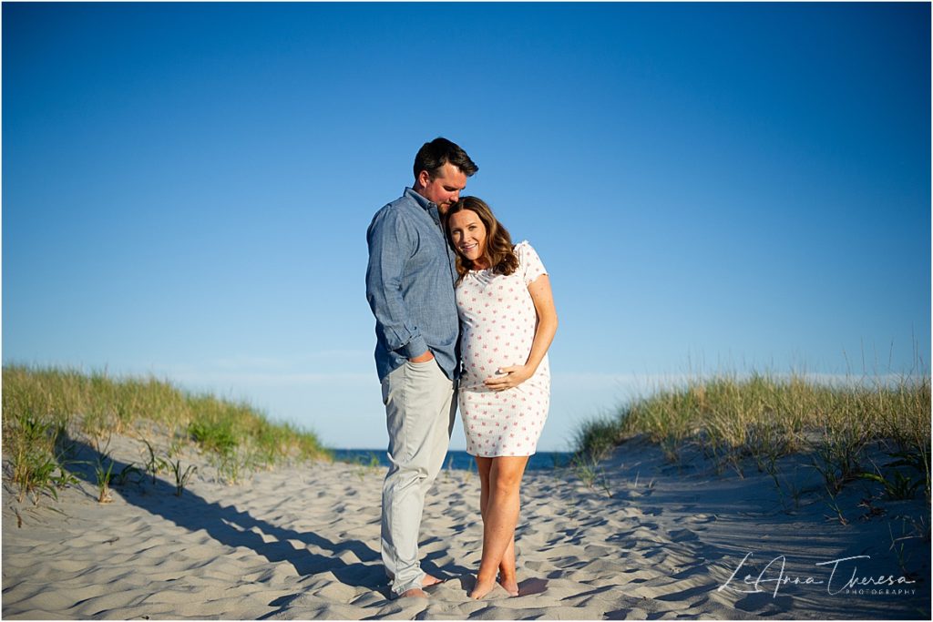 couple embrace for maternity photos at beach on LBI